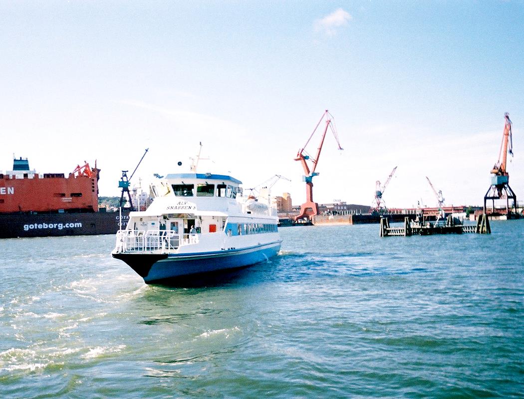 A ferry moves through a crowded seaport.
